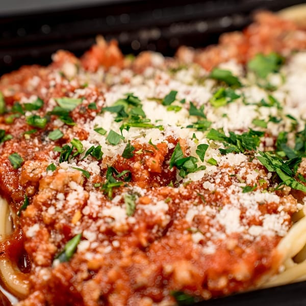 Close-up of spaghetti with meat sauce, parmesan cheese, and fresh parsley from Victoria's Kitchen.
