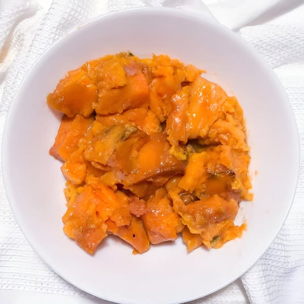 A white bowl filled with glistening, orange candied yams from Victoria's Kitchen & Catering.